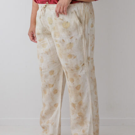 A woman wears cream linen trousers that have been eco printed with brown and yellow eucalyptus leaves
