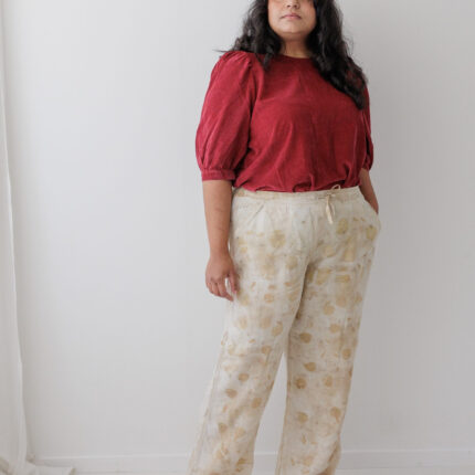 A woman wears cream linen trousers that have been eco printed with brown and yellow eucalyptus leaves