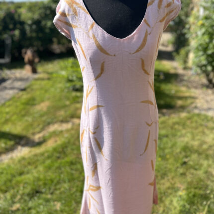 Pale pink wool crepe dress with soft low V neck ecprinted with orange eucalyptus leaves cascading down each side of the dress