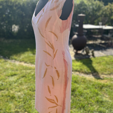Pale pink wool crepe dress with soft low V neck ecprinted with orange eucalyptus leaves cascading down each side of the dress