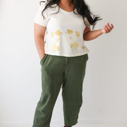 A happy woman wears a cotton white V neck T shirt eco printed with yellow rose leaf prints